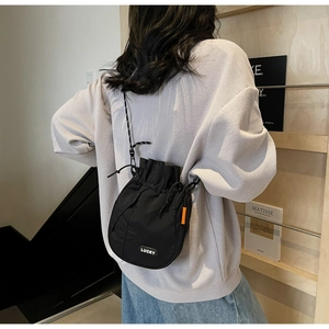 Detail view of black drawstring bucket bag featuring a woven LUCKY label and orange side tag