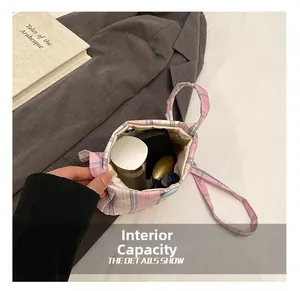 Detail of pink plaid tote bag interior showing spacious capacity for cosmetics and books