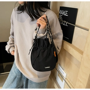 Detail of black drawstring bucket bag with LUCKY logo and woven rope handle on model