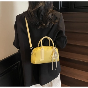 Detail of yellow Boston handbag with lychee pattern and pearl ribbon charm decoration