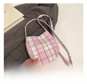 Detail show of plaid fabric crossbody bag with blue button closure on a grey suit