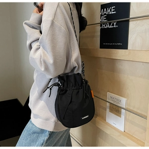 Detail of black nylon drawstring bucket bag with Lucky patch and slender shoulder strap