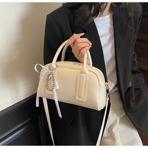 Cream Boston bag detail featuring textured leather, a silk bow, and a detachable strap