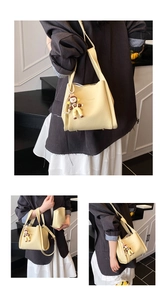 Dettaglio della borsa tote in pelle grana litchi giallo crema con ciondolo a cartone