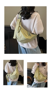 Detail of olive green crescent bag featuring wide shoulder strap and woven zipper puller