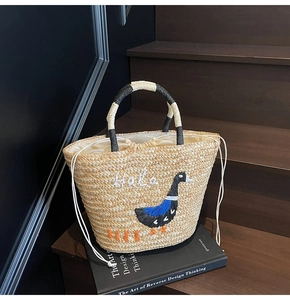 Detail of handmade straw beach bag with Hola duck embroidery and drawstring closure