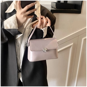 Detail of lavender oil wax leather handbag with silver round lock held by model