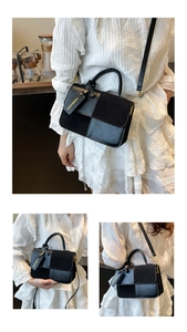 Close-up of black crossbody bag with mixed leather textures and decorative fashion tag