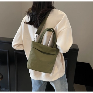 Olive green tote bag with adjustable strap shown on model in a casual lifestyle setting