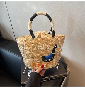 Detail of woven straw handbag featuring Haba letter embroidery and drawstring closure