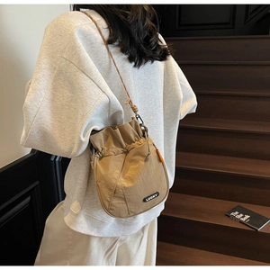 Close-up of khaki drawstring bucket bag with lucky patch embroidery and nylon texture