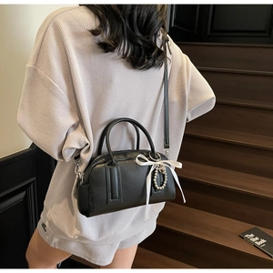 Chic black Boston bag with white ribbon and pearl heart charm shown on model back