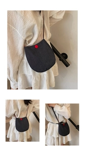 Macro detail of the U-shaped denim canvas crossbody bag with red decorative button accent