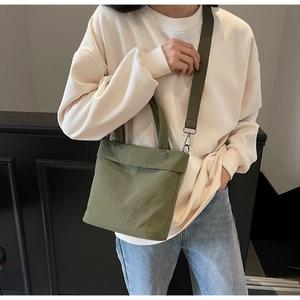 Detail of green nylon tote bag featuring adjustable shoulder strap and metal hardware