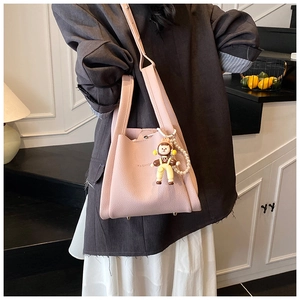 Detail of pink lychee grain handbag with cute doll charm and large pearl decorative chain