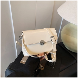 Detailed macro view of the cream-colored square bag with a silver circular swivel lock
