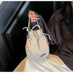 Detailed close-up of cream nylon drawstring bag with cotton rope handle and Lucky label