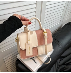 Detail of the contrast color handbag with golden square buckle and premium textured finish