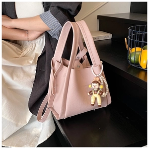 Pink lychee grain leather bucket bag with fashion logo and decorative doll pendant