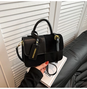 Detail of black leather handbag featuring suede panels and elegant rounded top handle