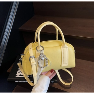 Detail of light yellow Boston bag with lychee texture leather and silver heart charm