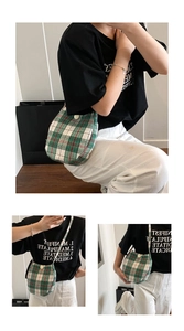 Detail view of green plaid fabric crossbody bag with white button and curved bottom design