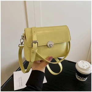 Detail of light yellow square bag featuring silver rotary lock and smooth leather texture