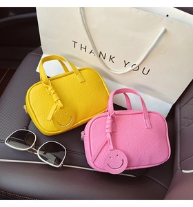 Detail of yellow and pink pebble leather mini satchel bags with cute smiley face pendants