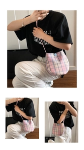 Detail of pink plaid crossbody bag showing fabric texture and blue button closure