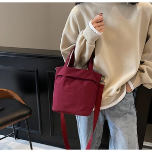 Detailed view of casual red canvas tote bag with detachable crossbody strap worn by model
