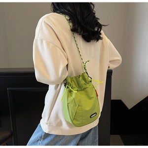 Macro shot of a neon green nylon bucket bag featuring a woven strap and Lucky tag