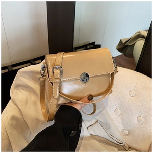 Close-up of beige oil wax leather handbag with a stylish round metal twist lock detail