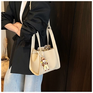 Detail of cream lychee texture bucket bag with Fashion text and cute doll charm