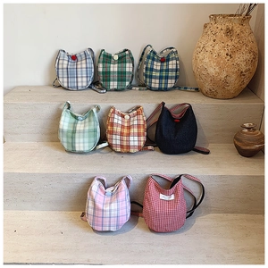 Detailed display of assorted plaid and solid fabric crossbody bags on stone steps