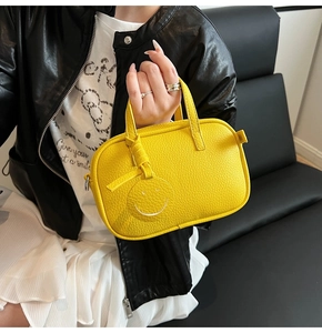 Detail of yellow lychee grain leather pillow bag with a matching smile charm
