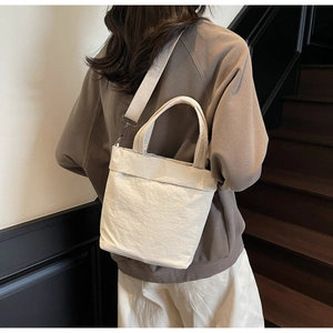 Detail of minimalist beige nylon tote bag with pleated texture and adjustable strap