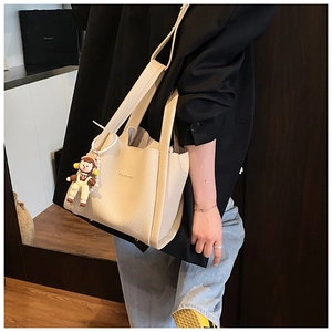 Detail of off-white lychee texture bucket bag with Fashion lettering and adjustable strap