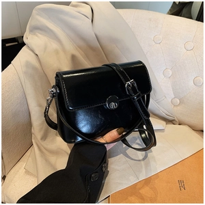 Detail of black oil wax leather handbag with silver round twist lock and adjustable strap