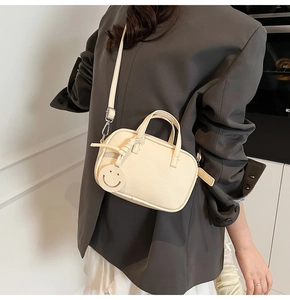 Chic cream white mini pillow bag with lychee texture and smiley charm on a fashion model