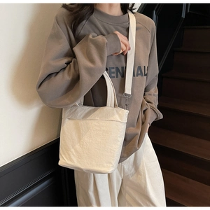 Detailed view of white minimalist nylon tote with adjustable strap and textured fabric