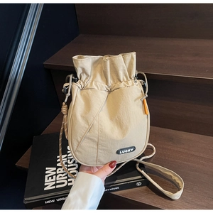 Detailed close-up of beige nylon bucket bag with Lucky patch on a design book