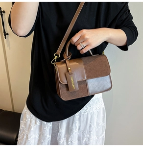 Detail of dark brown leather crossbody bag featuring contrasting textured suede panels