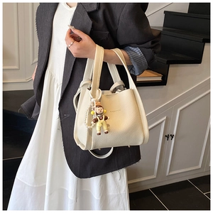 Detail of cream white lychee pattern bucket bag with pearl chain and fashion logo