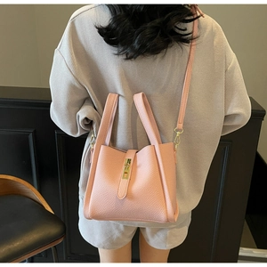 Vue arrière du mannequin portant un sac seau rose en cuir grainé avec boucle dorée