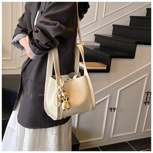 Detail of off-white lychee texture leather tote bag with stylish doll and pearl chain