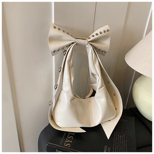 Nahaufnahme einer weißen glänzenden Ledertasche mit Nieten und großer Schleife