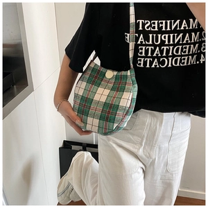Detail of green plaid canvas shoulder bag with secure button closure and durable strap