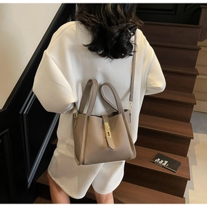 Sac seau en cuir motif litchi avec ferrures dorées sur une tenue blanche