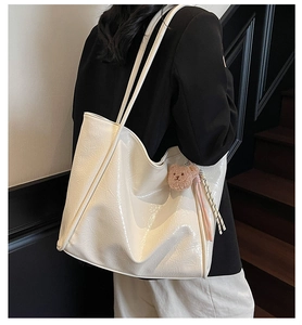 Detail of cream white oil wax leather tote bag with glossy texture and teddy bear charm