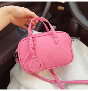 Close-up of pink lychee leather pillow bag featuring a detachable smile pendant